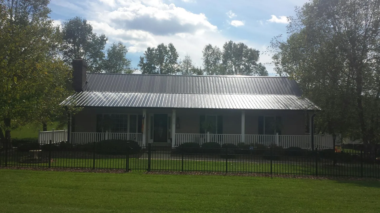 Gray metal roof on a brick ranch with a full width front porch — Gutter Guard Installation work by our crew in Fairfax